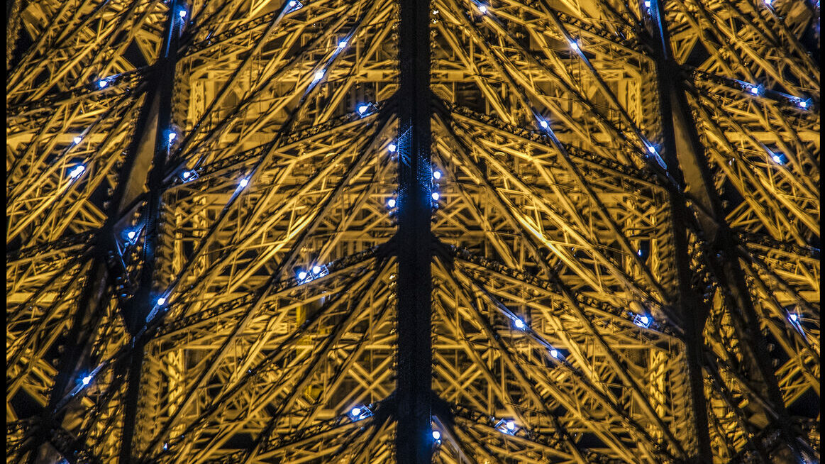 Gros plan sur l'armature de la tout Eiffel avec les lumières clignotantes du début d'heure