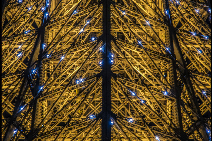 Gros plan sur l'armature de la tout Eiffel avec les lumières clignotantes du début d'heure